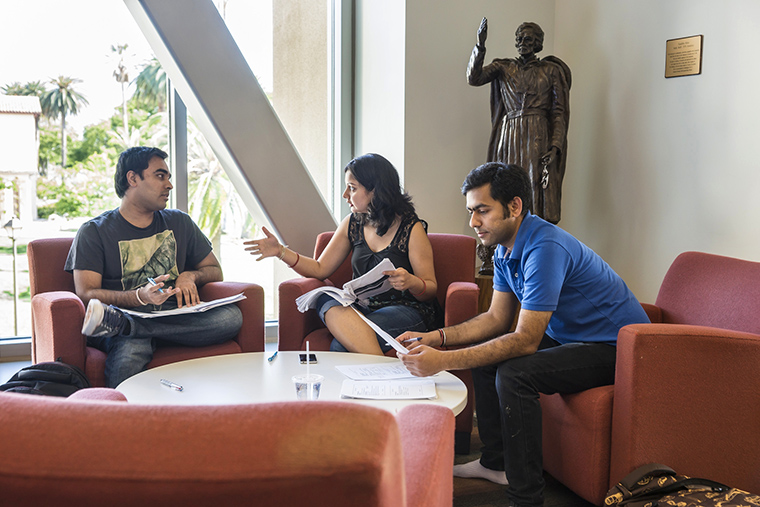 Three people sitting and conversing in a library lounge area.