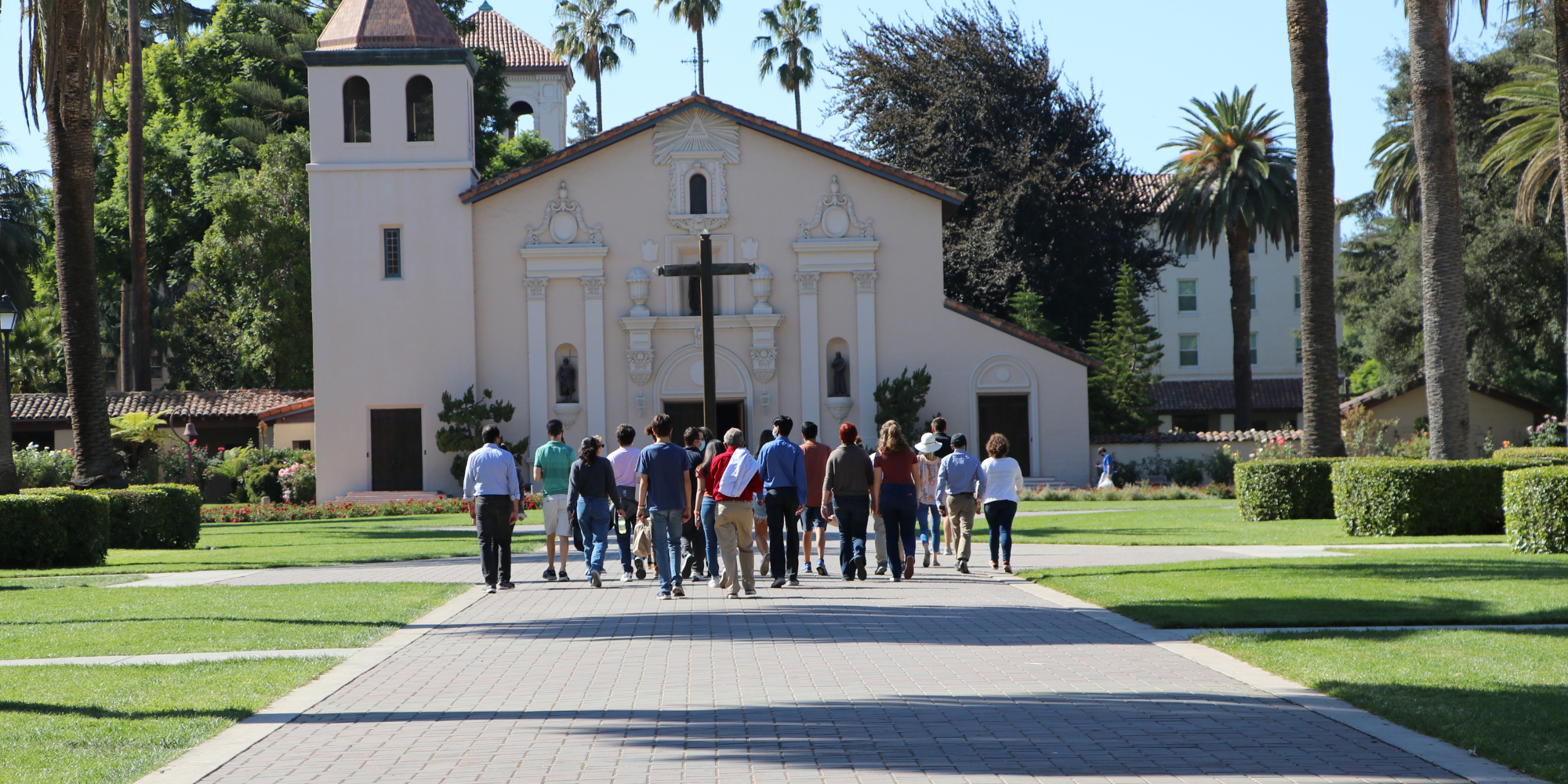 A group of people walking towards a church building on a sunny day. image link to story