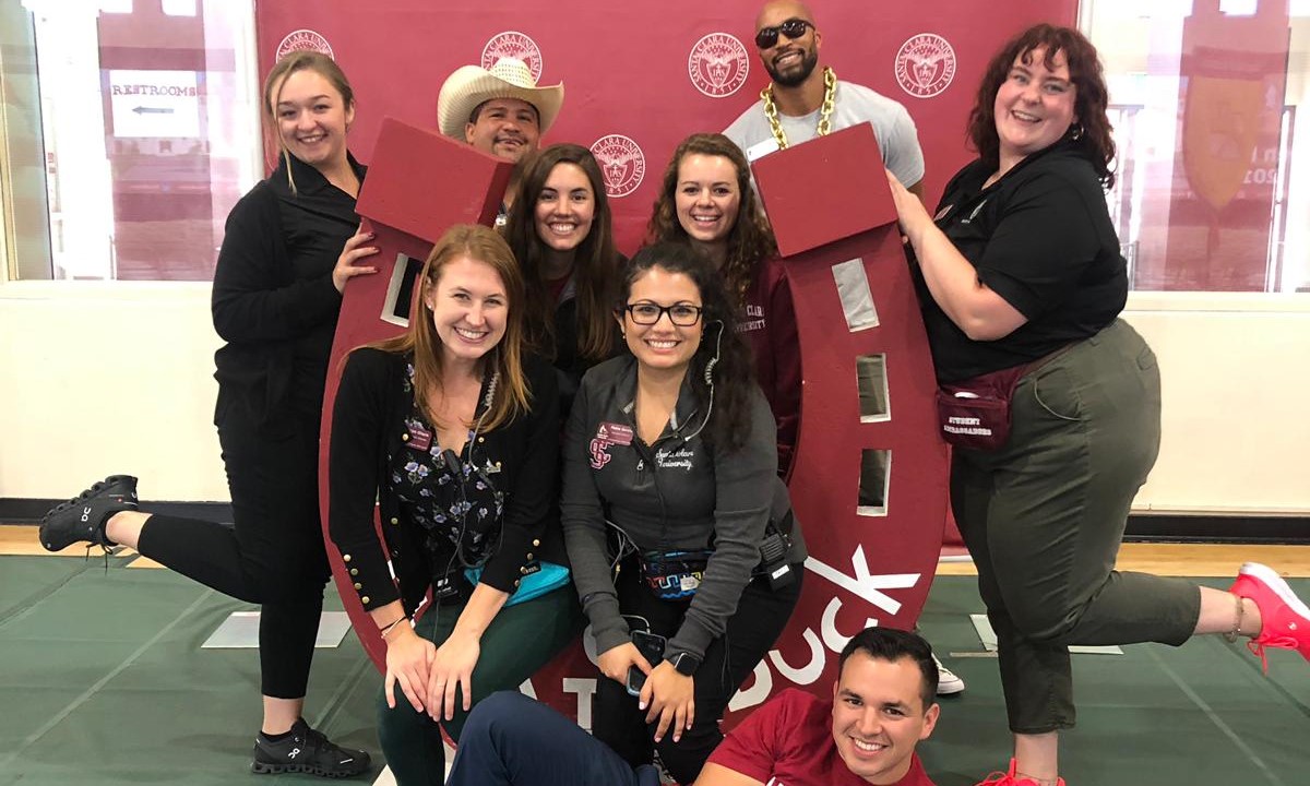 Group of people posing in front of a banner at an event. image link to story