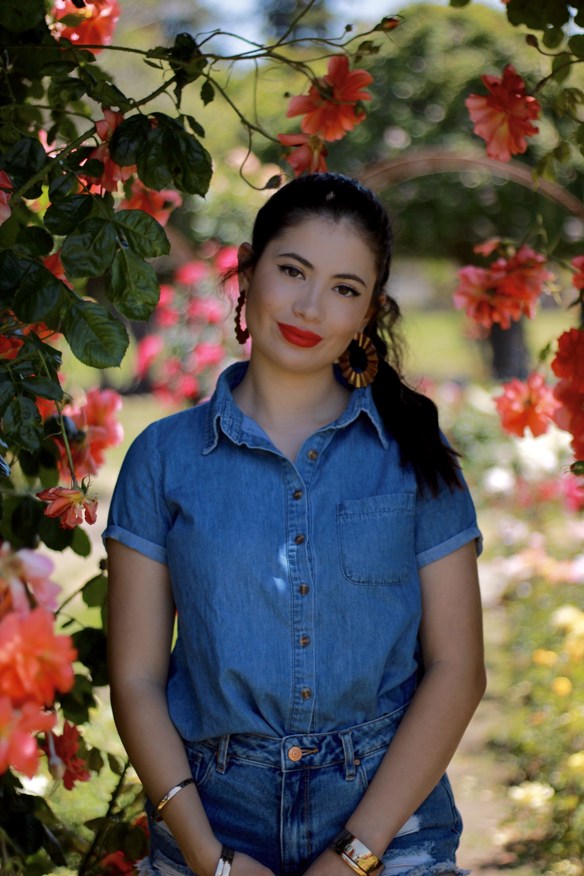 A person in a denim shirt standing in a garden.