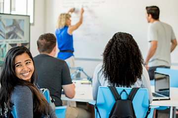Students in a classroom working on a whiteboard discussion.