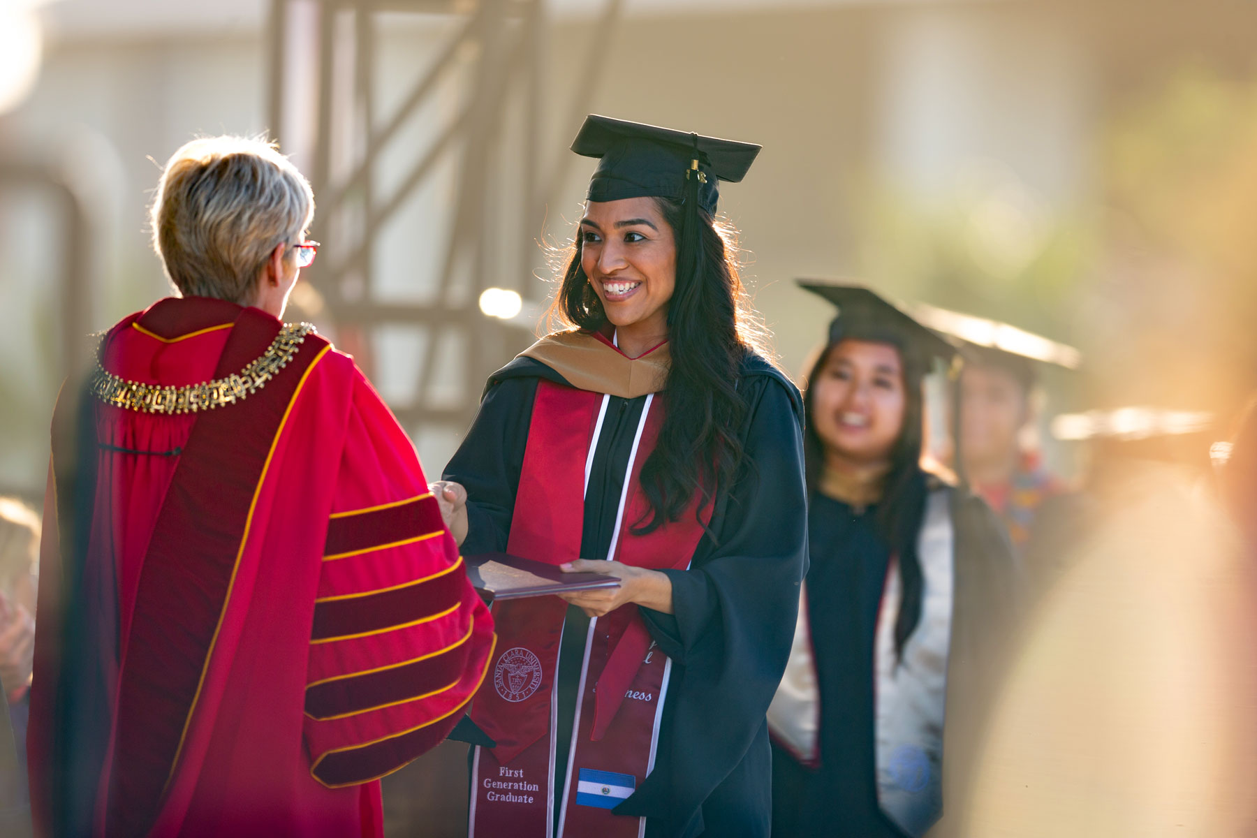 A first-gen graduate from Guatemala shakes hands with the president as she walks across the stage.