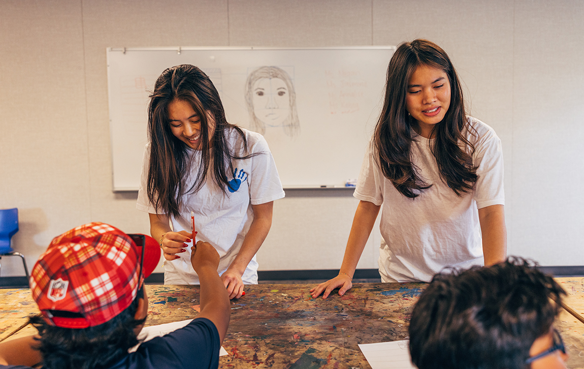 Megan Baldemor and Jasmine Vu work with students at table