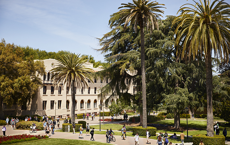 Photo looking down on OConnor Hall, palm trees, and students walking