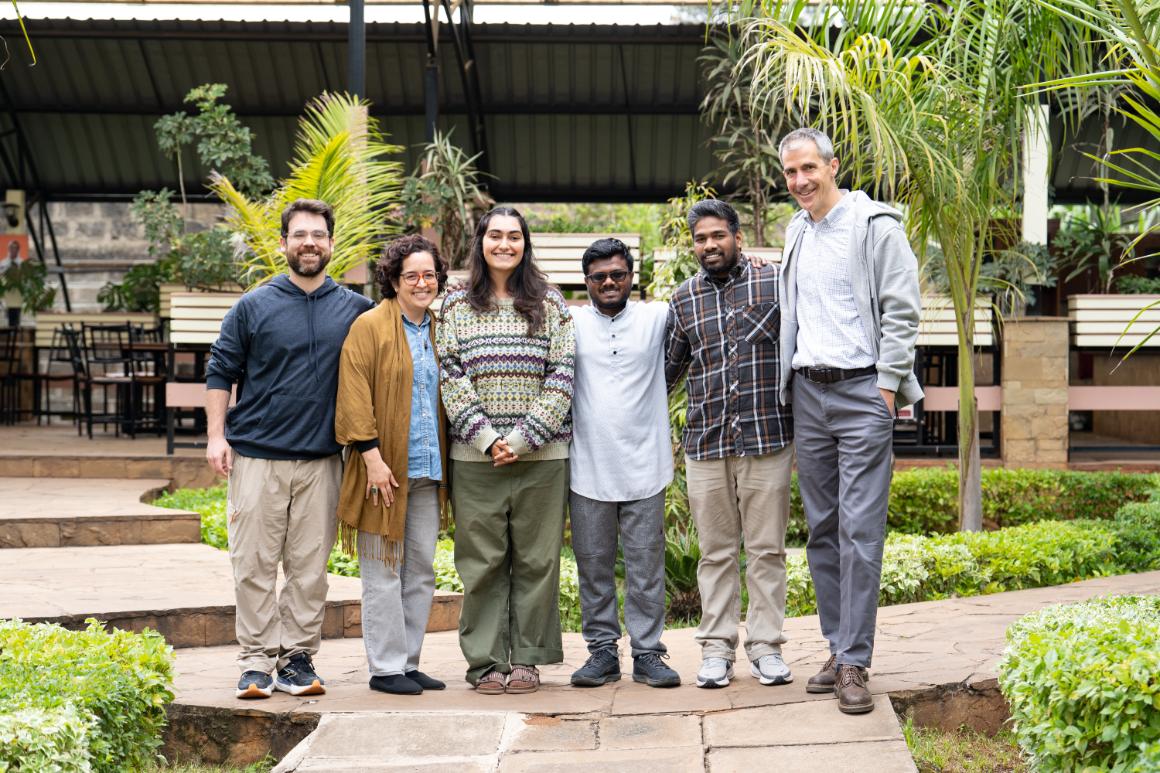 Four students and two staff members pose outdoors.