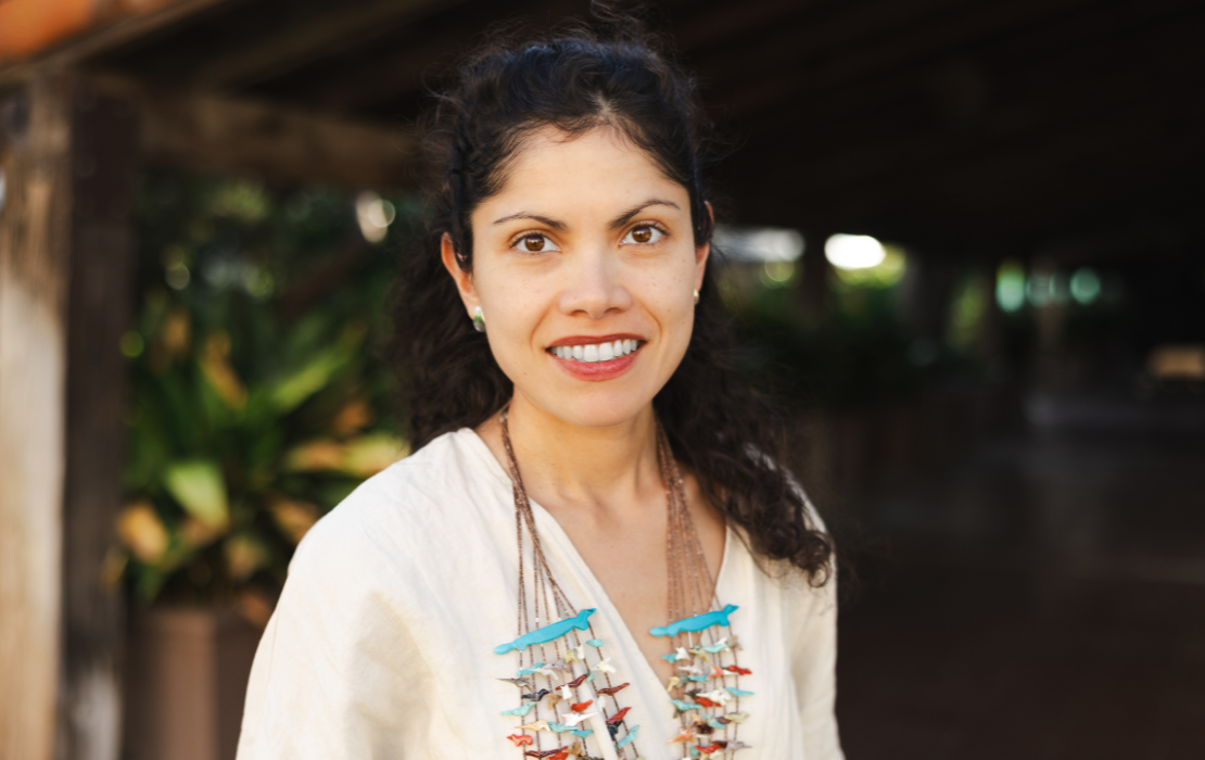 Associate professor Jesica Fernandez wearing a white blouse and multi-colored necklace