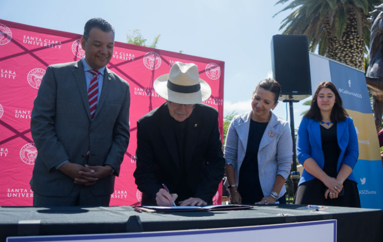 Fr. Engh in front of SCU sign, signing an MOU regarding voter registration