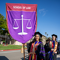 Law student holding school of law banner outside commencement