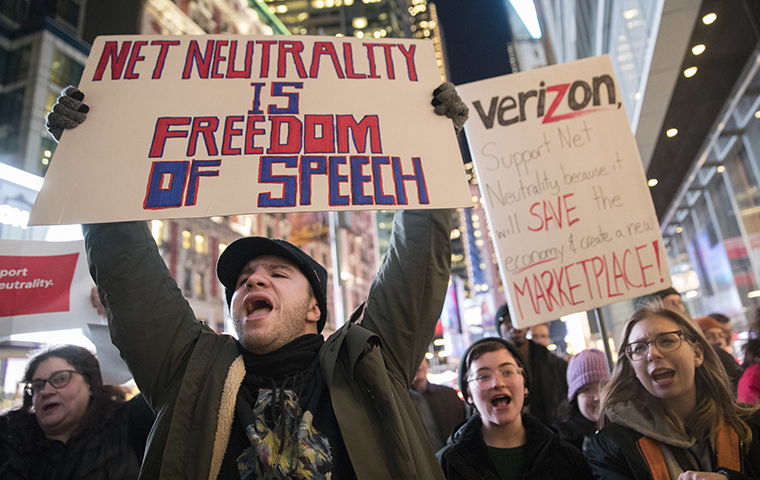 Man holding a sign protesting the abolishing of net neutrality