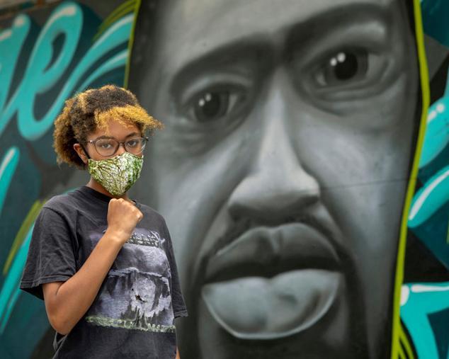 Jadyn Polk, 14, poses in front of a mural of George Floyd painted in downtown Oakland, Calif., Friday, June 5, 2020. Polk is the daughter of activist Cat Brooks and she participated in the peaceful student-led march of 15,000 people from Oakland Technical High School to City Hall. (Karl Mondon, Bay Area News Group)