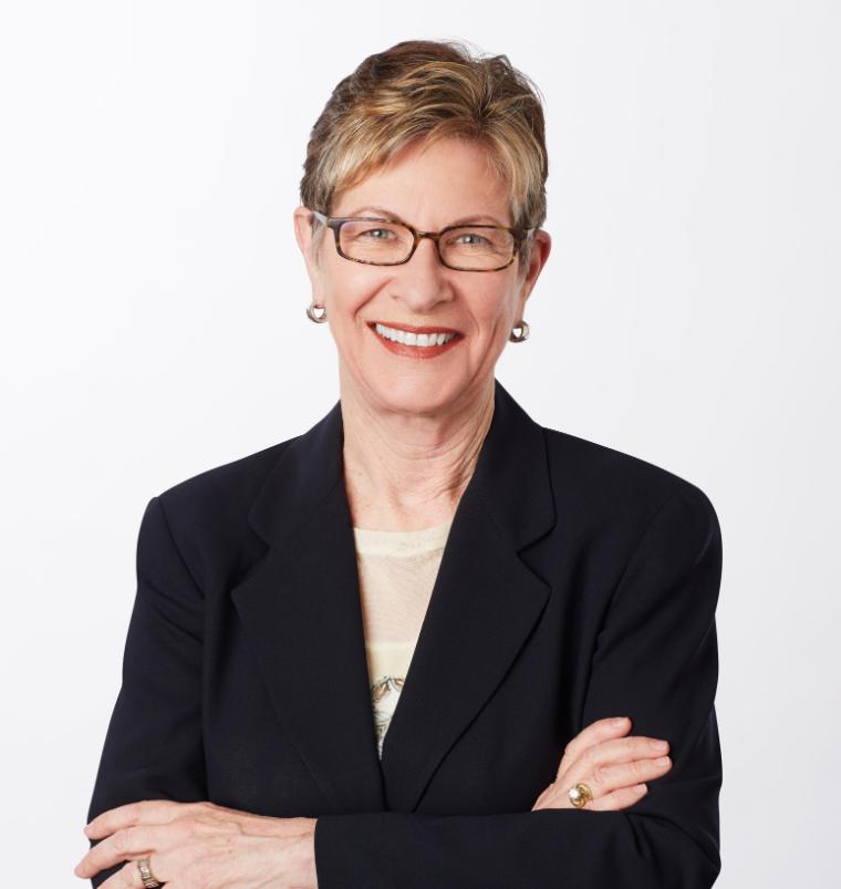Person in a suit with arms crossed, against a white background.