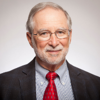 Headshot of a man with glasses, wearing a suit and red tie.