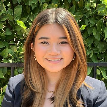Woman in black blazer outdoors smiling