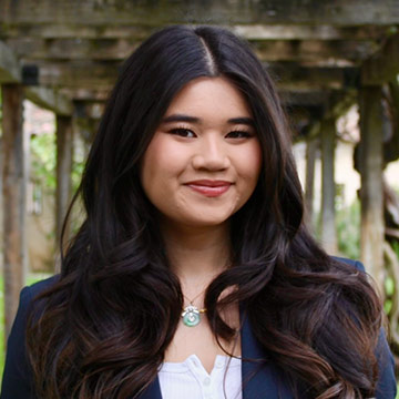 Woman in black blazer outdoors smiling