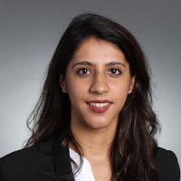 A person in formal attire against a gray background.