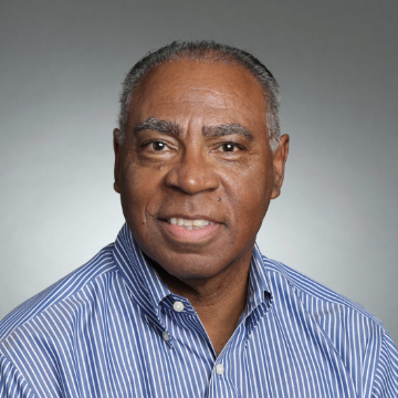 A person wearing a blue striped shirt, smiling at the camera.