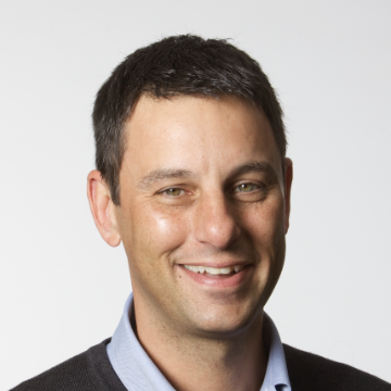 A person smiling with a light background.