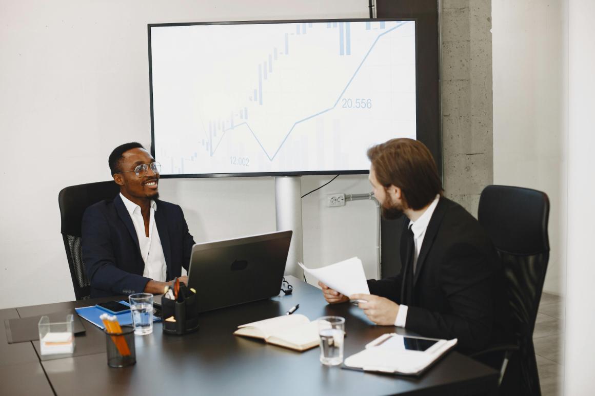 Two business professionals discussing graphs during a meeting