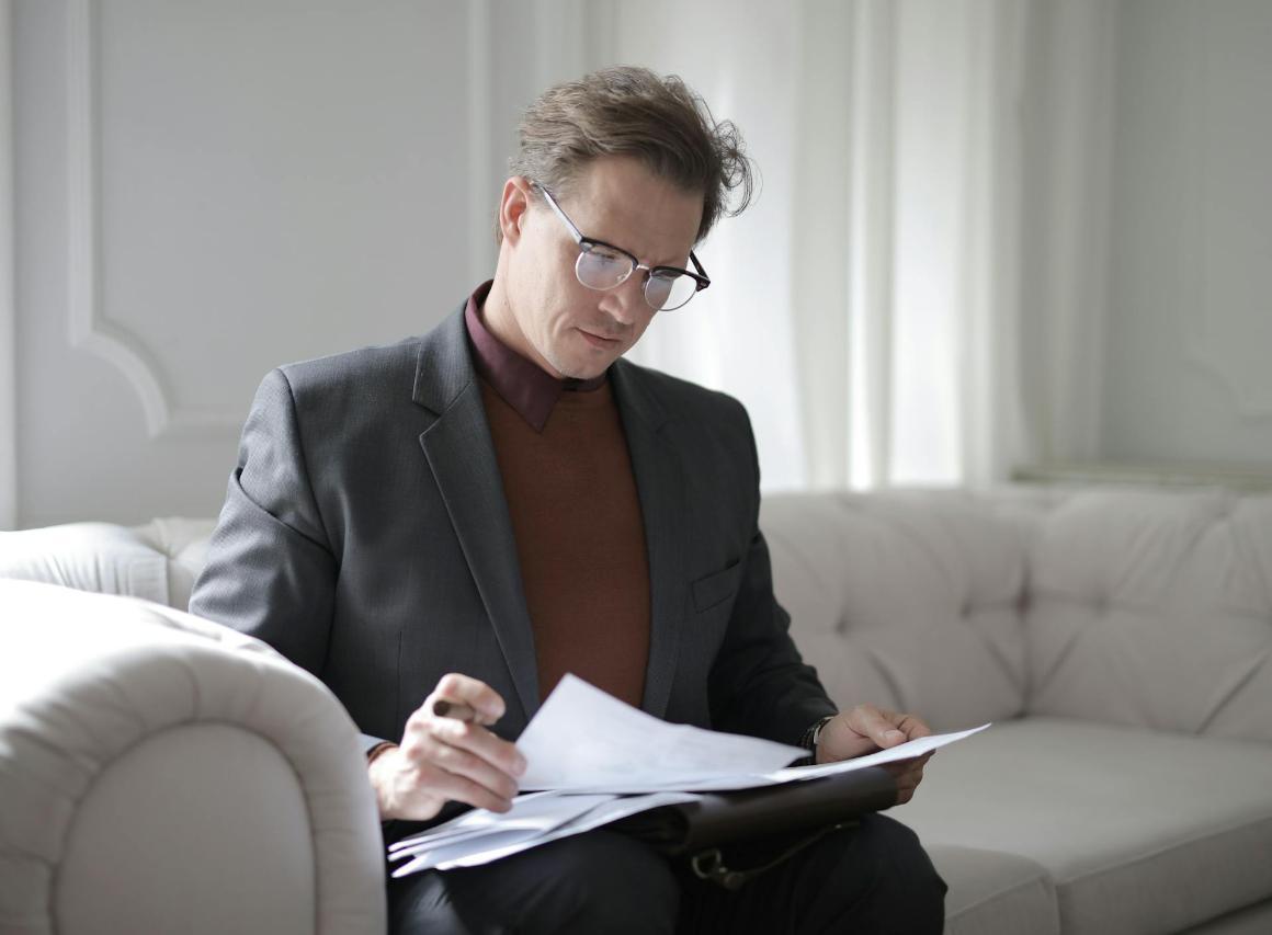 Business professional sitting on couch, looking through papers strategically