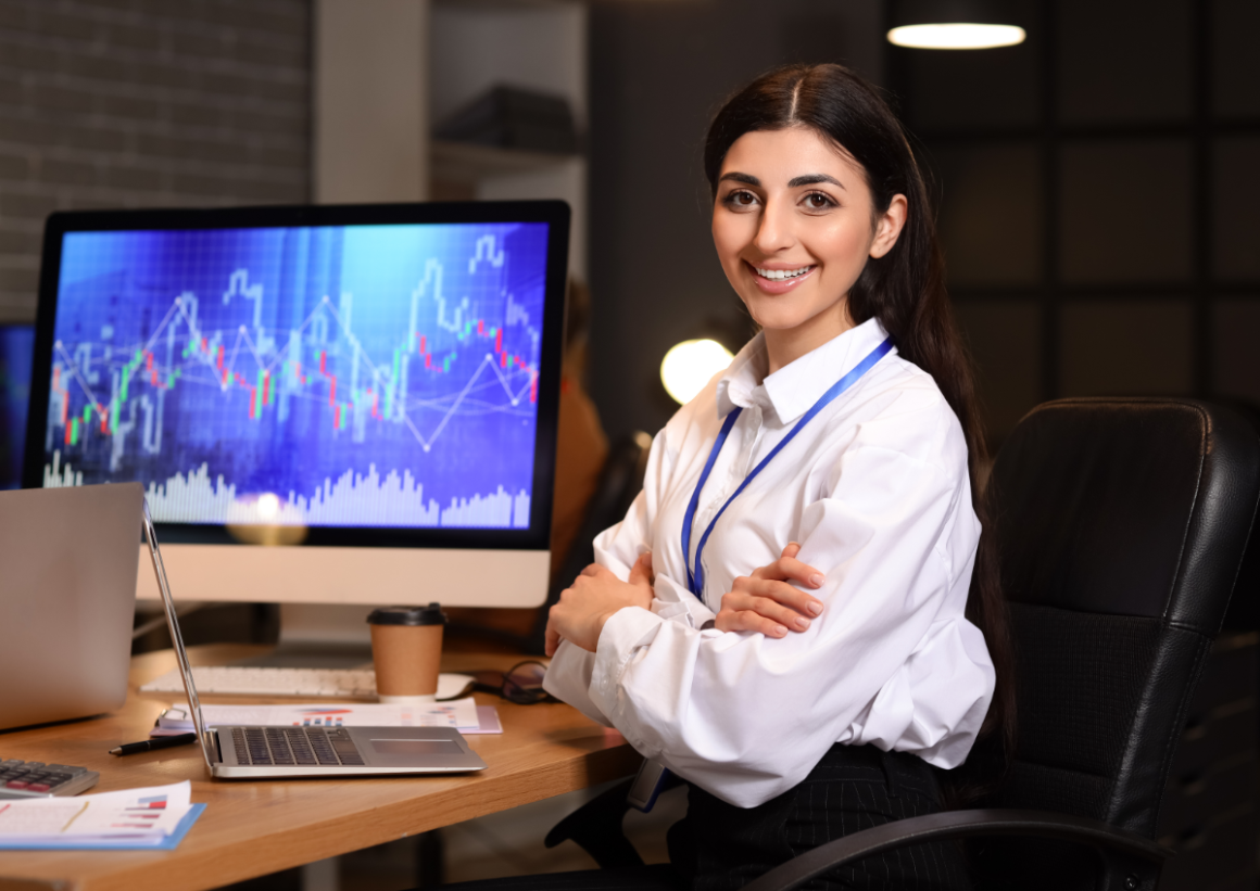 Business professional with arms crossed sitting in front of open laptop