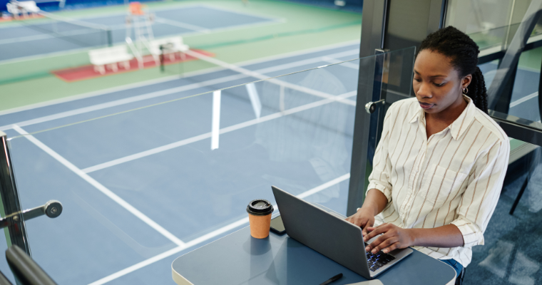 Business professional working on laptop with tennis courts in the background