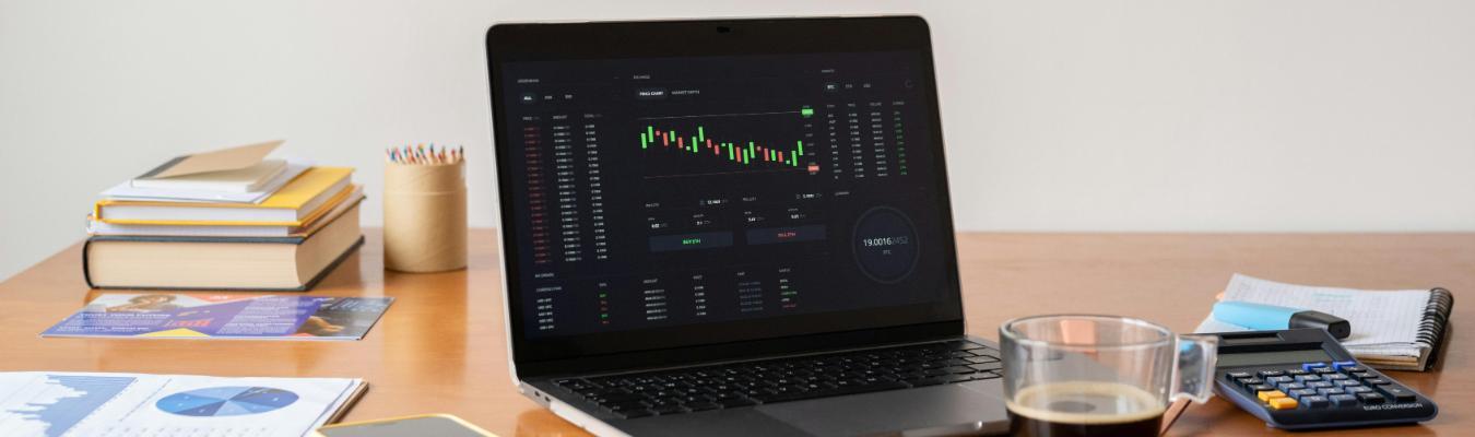 Laptop open on desk displaying stock and financial dashboard