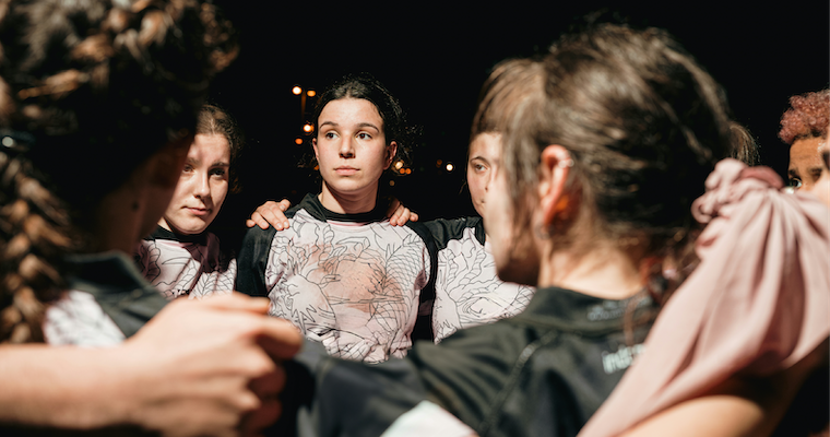 Women's athletes team huddle during a night game