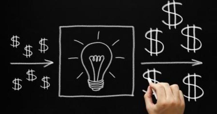 A hand draws a sketch of a light bulb going off and money signs.