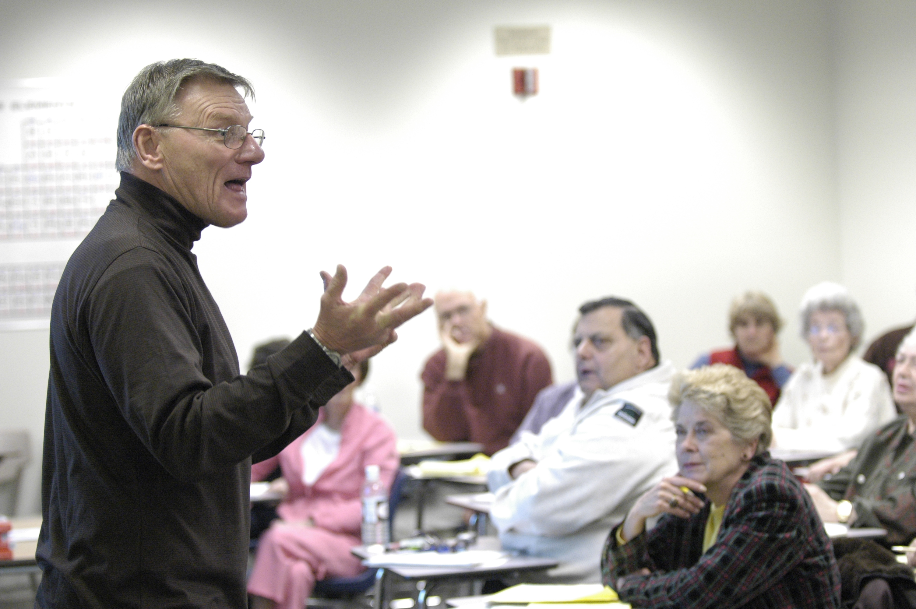 A lecturer addressing students in a classroom setting.