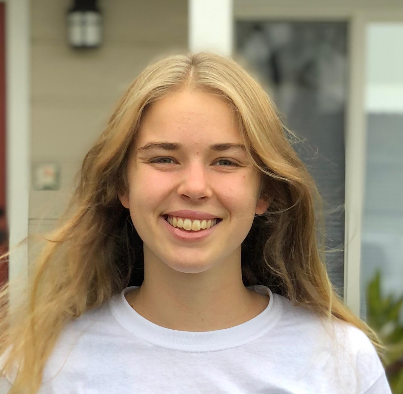 Individual standing outside a building, wearing a white Snuggle is Real sweatshirt.