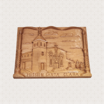 A wooden plaque, on which is carved an image of Mission Santa Clara de Asís, under which is inscribed Mission Santa Clara. Smaller text just above reads J Perrotta 8-7-1971.