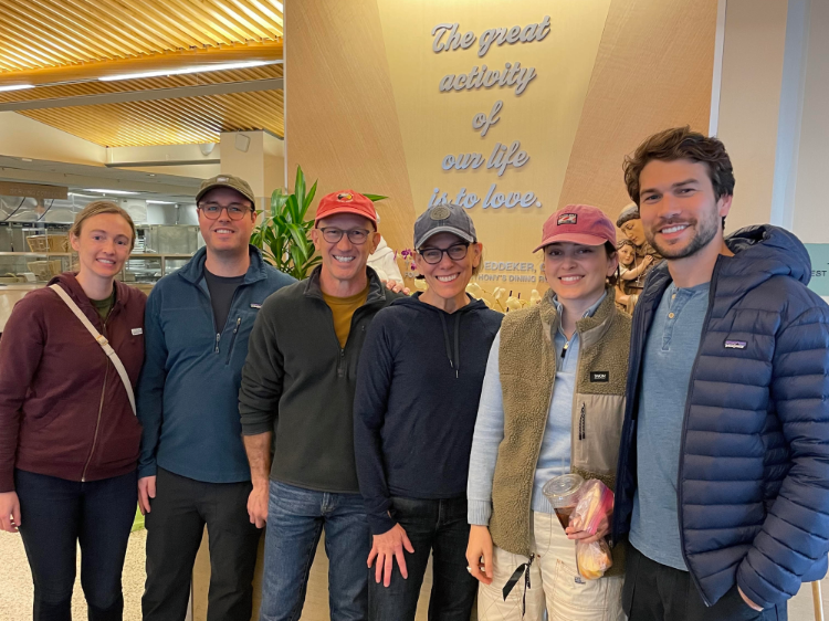 A group of smiling people in front of a sign that says The great activity of our life is to love.