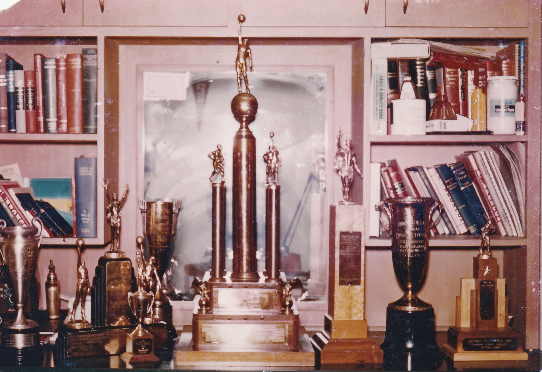 A vintage photo from 1957 of several USF sports trophies on a bookshelf