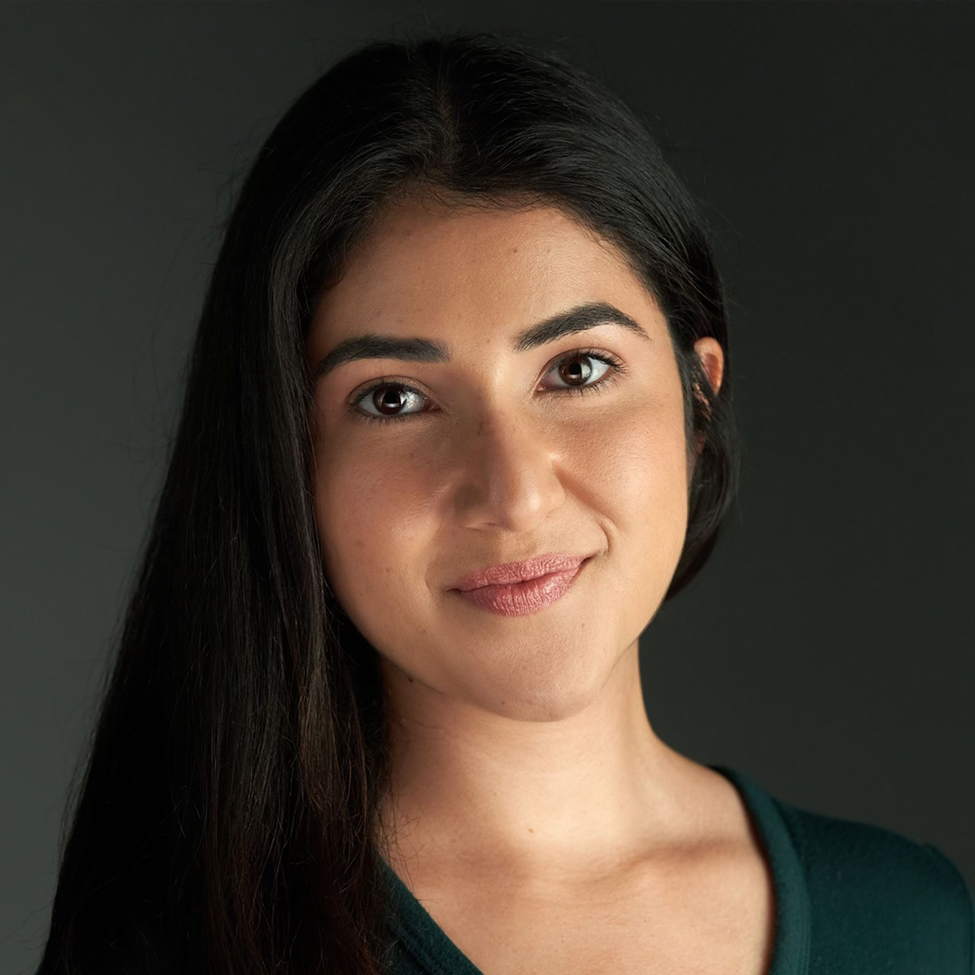 A young, smiling woman in front of a dark background.