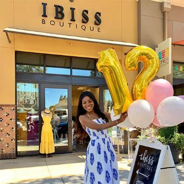 Woman holding balloon bouquet in front of Ibiss restaurant entrance.