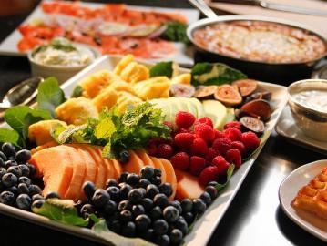 A platter of assorted fruits including blueberries, strawberries, raspberries, pineapple, and greens.