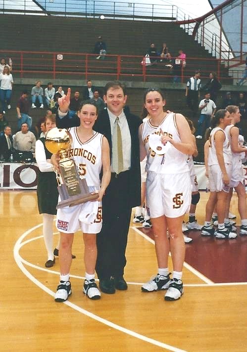 A group of basketball players and a coach on a court.