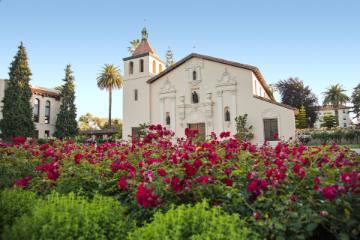 A historical mission church with gardens in the foreground.