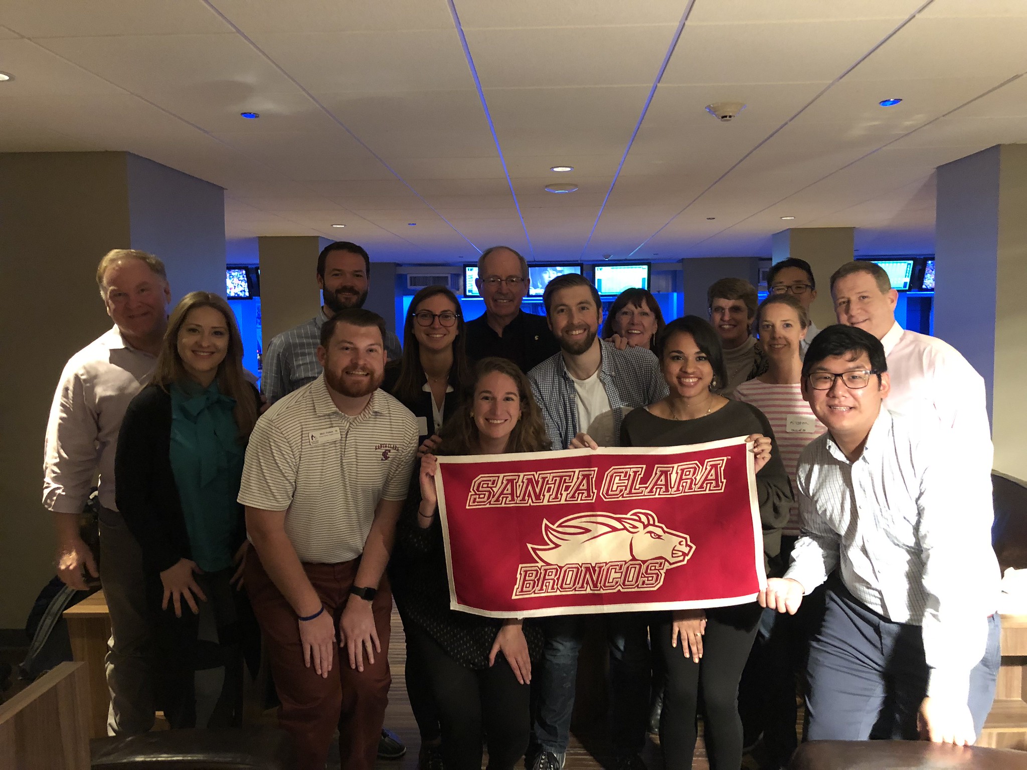 Chicago Alumni in a bowling alley holding a Santa Clara Broncos banner