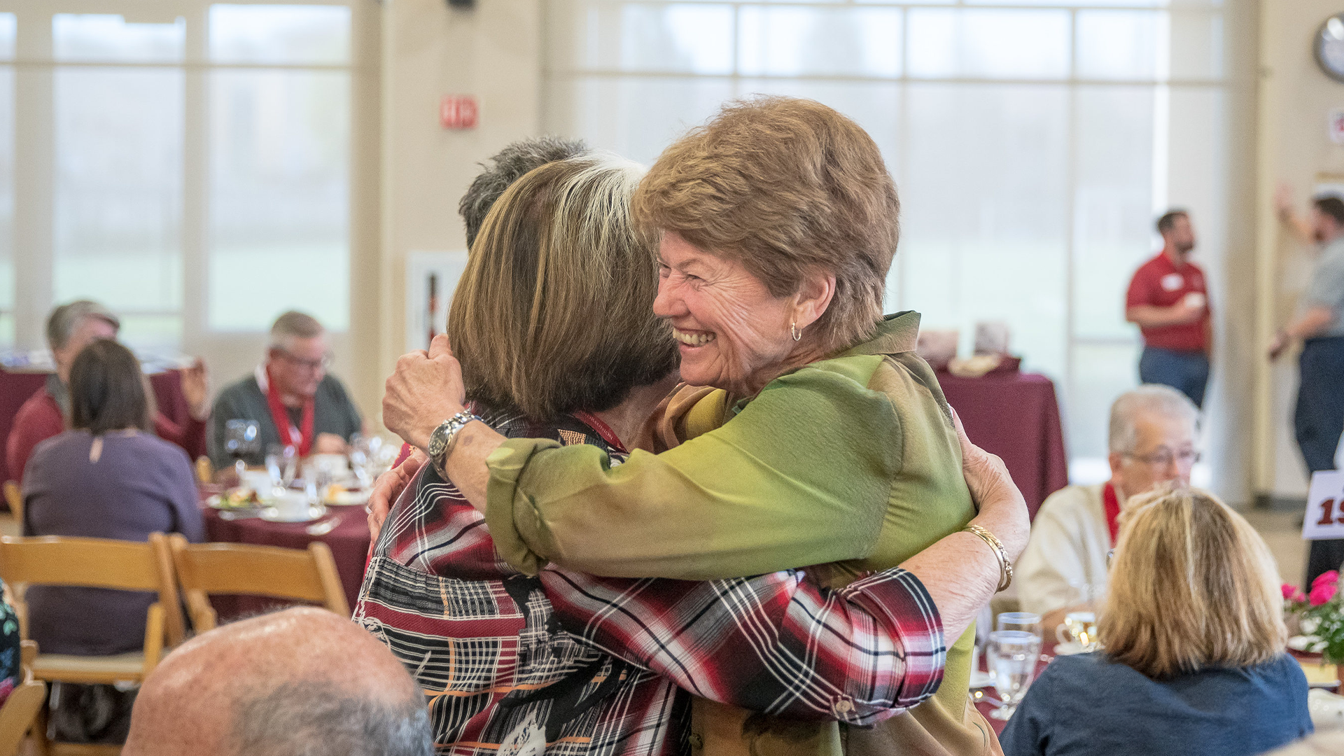 Two older alumni hug at the Gianera Lunch
