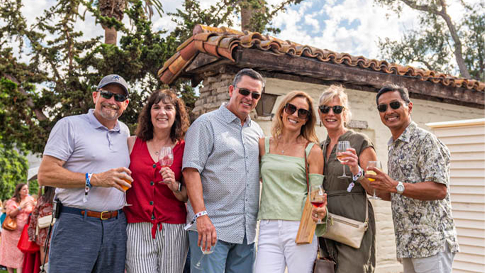 A group of alumni in front of the adobe wall