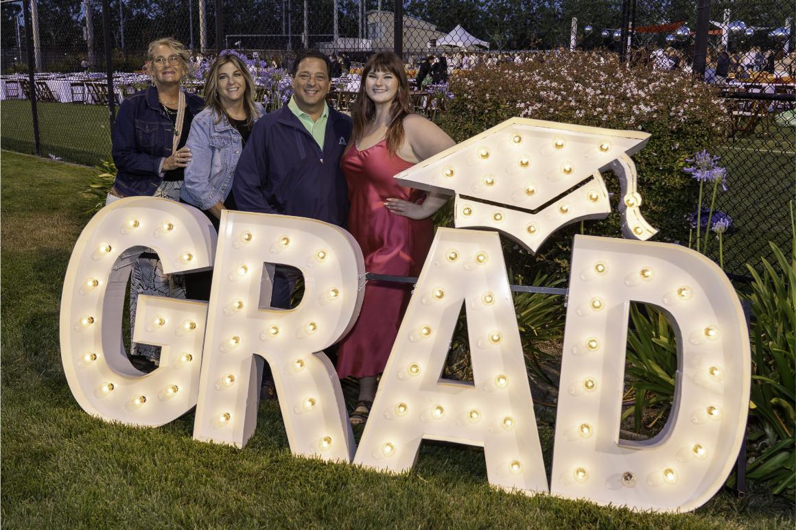 A family posing with large, light-up letters spelling out GRAD at Grad Bash 2025.