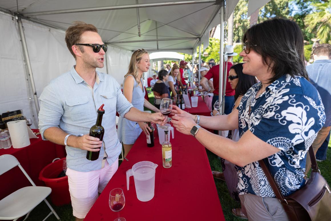 A wine vendor hands a glass of wine to a guest 