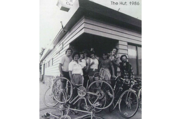 Group of people with bikes in front of a hut, 1986.