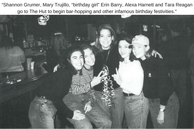 Four people posing together in a dimly lit room with text above them.