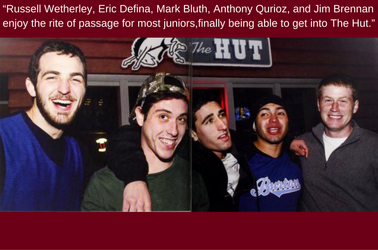 Five people smiling in front of a sign reading 2013 Hut. Text on image.