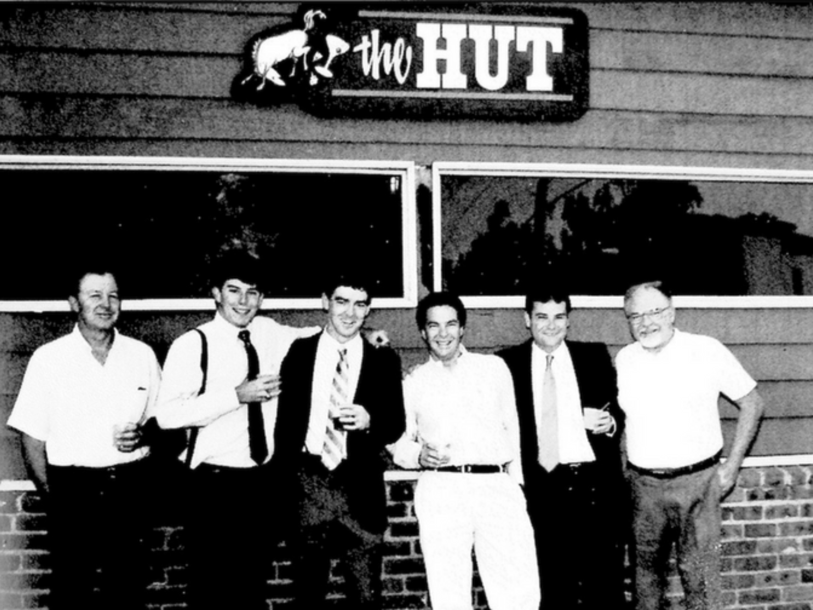 Six men stand in front of The Hut, a local SCU bar 