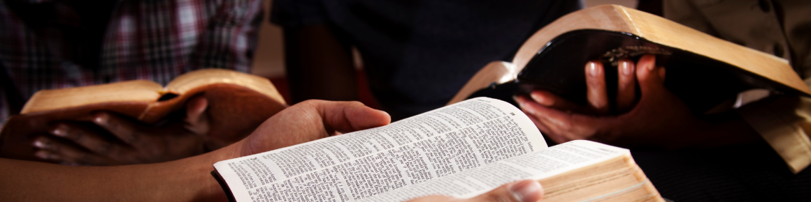 close up of hands holding bibles reading Scripture 