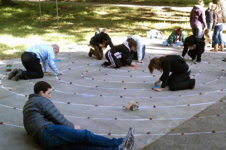 People engaged with a labyrinth on a stone pathway at a retreat.