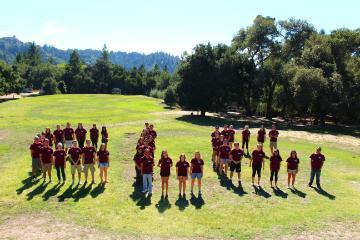 People forming the letters CLC on a grassy field.